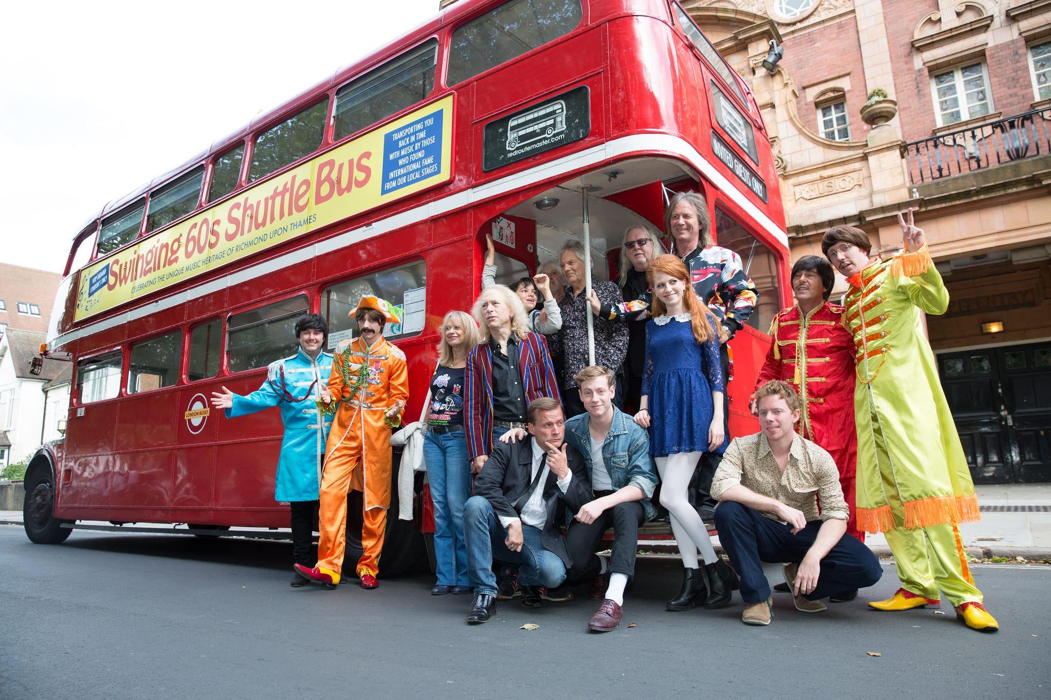 A group of people, some in fancy dress, standing infront of a red routemaster redroutemaster.com bus