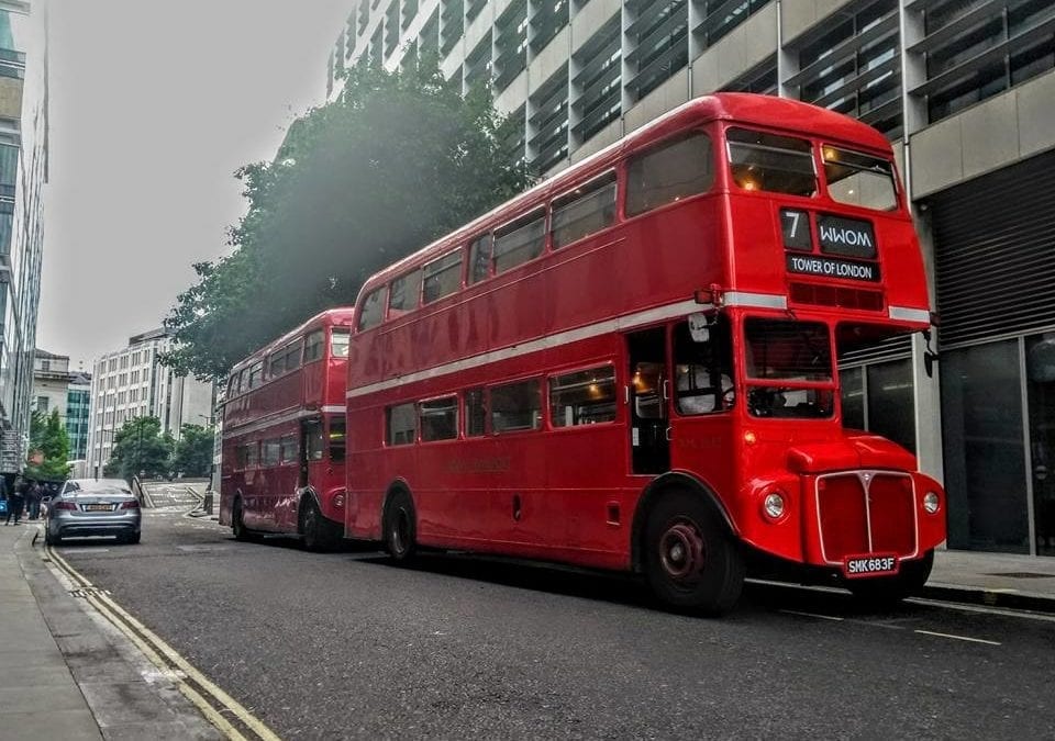 Two Routemaster buses outside a large building heading for the Tower of London