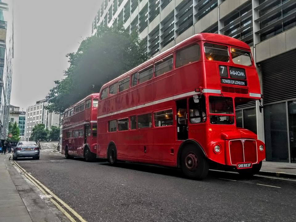 Two Routemaster buses outside a large building heading for the Tower of London