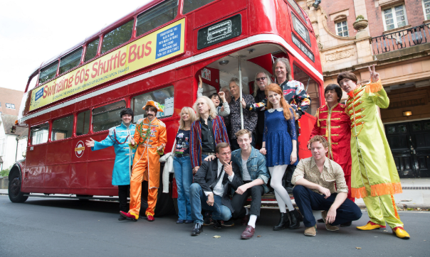 A group of people, some in fancy dress, standing infront of a red routemaster redroutemaster.com bus